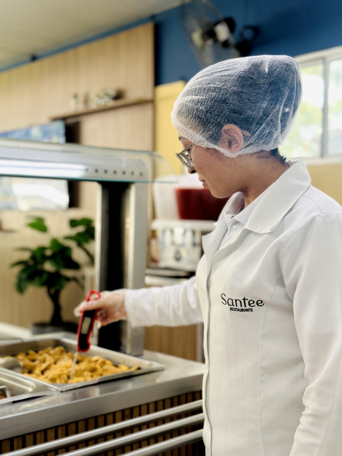 Colaboradora da Santé medindo temperatura da comida.